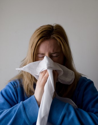 Femme qui se mouche, elle a la grippe